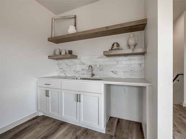 bar with light wood-type flooring, lofted ceiling, sink, and white cabinets