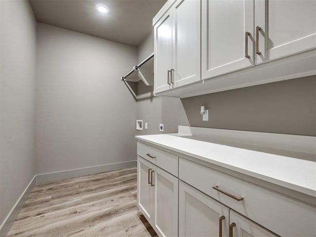 washroom with cabinets, electric dryer hookup, hookup for a washing machine, and light hardwood / wood-style flooring