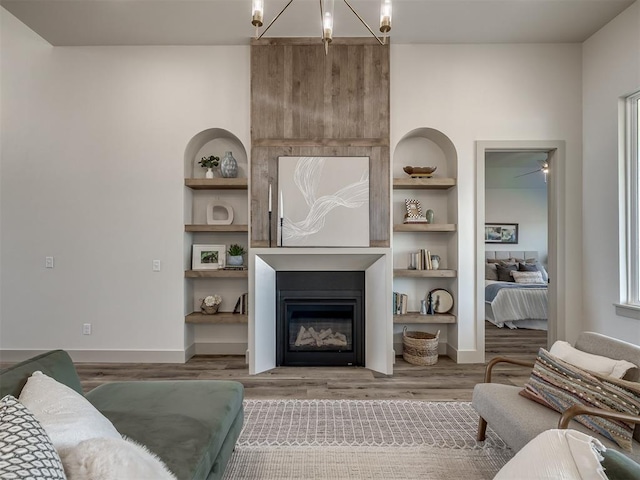 living room with hardwood / wood-style floors, built in features, and an inviting chandelier