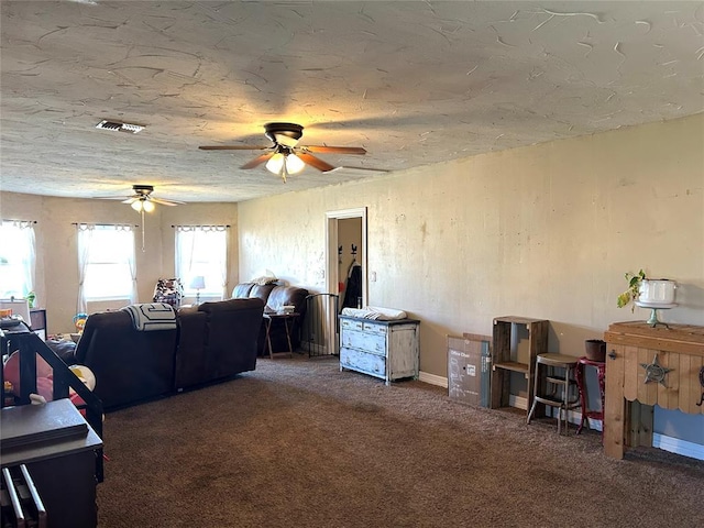 living room with ceiling fan, a textured ceiling, and dark colored carpet