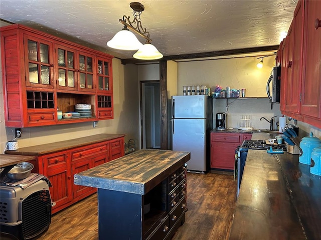 kitchen featuring stainless steel range with gas cooktop, wood counters, decorative light fixtures, dark hardwood / wood-style flooring, and fridge