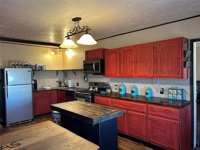 kitchen with pendant lighting, sink, stainless steel appliances, dark hardwood / wood-style floors, and a center island