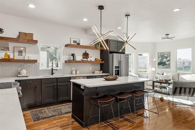 kitchen featuring high quality fridge, decorative light fixtures, a breakfast bar, and sink