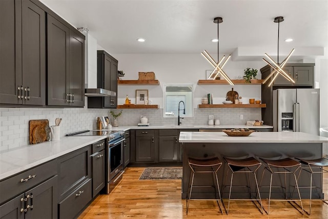 kitchen with a kitchen bar, sink, pendant lighting, stainless steel appliances, and decorative backsplash