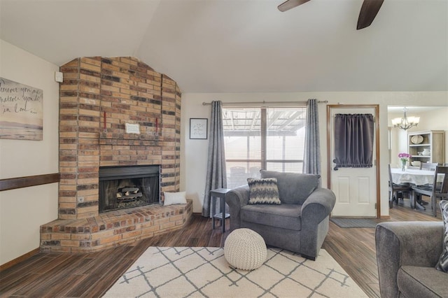 living room featuring lofted ceiling, hardwood / wood-style floors, ceiling fan with notable chandelier, and a fireplace