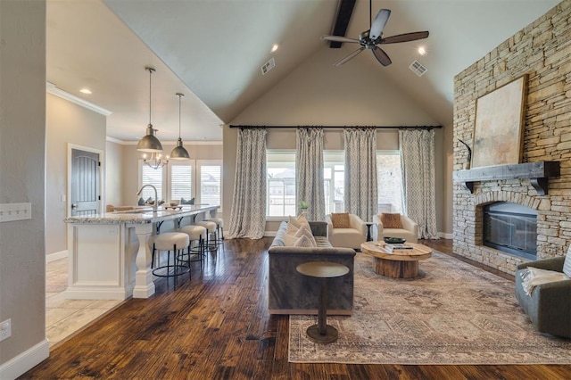 living room with lofted ceiling, crown molding, dark hardwood / wood-style floors, ceiling fan, and a fireplace