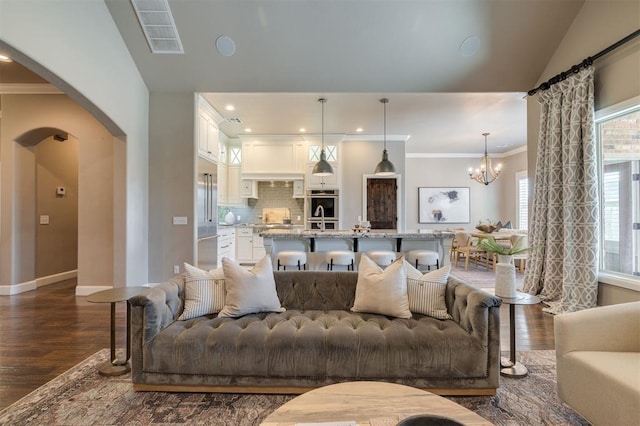 living room with plenty of natural light, dark hardwood / wood-style flooring, vaulted ceiling, and a notable chandelier