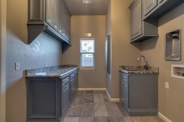 kitchen featuring dark stone countertops, sink, and gray cabinetry