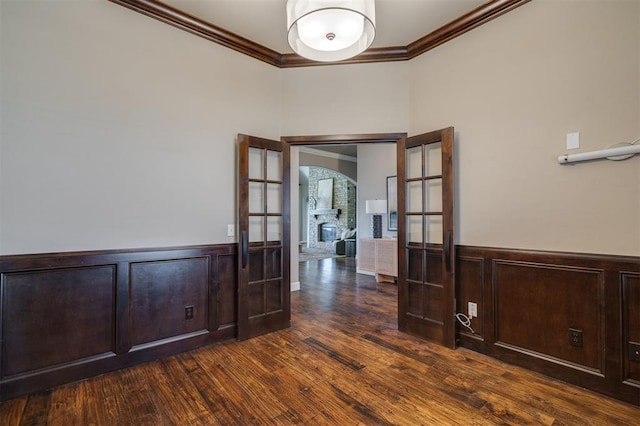 unfurnished room featuring crown molding, dark wood-type flooring, and a large fireplace