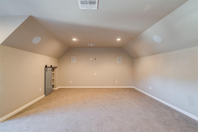 additional living space with lofted ceiling, light carpet, and a barn door