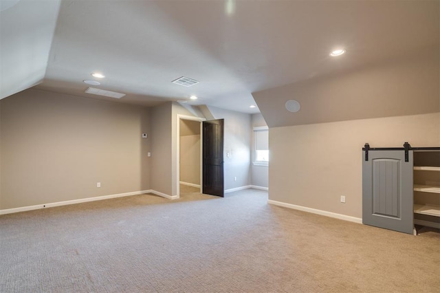 bonus room featuring lofted ceiling, light carpet, and a barn door