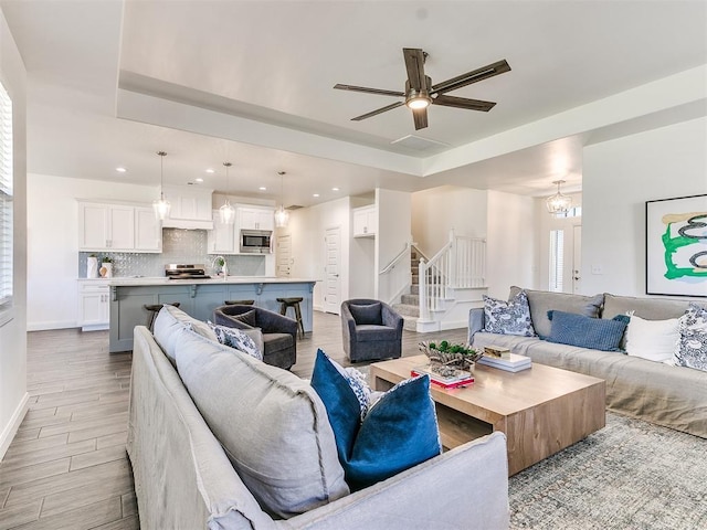 living room featuring sink, ceiling fan, and a tray ceiling