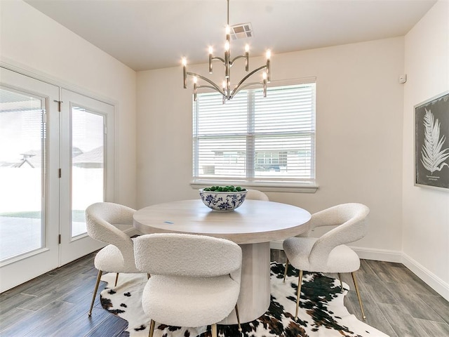 dining area with hardwood / wood-style flooring, plenty of natural light, and a chandelier