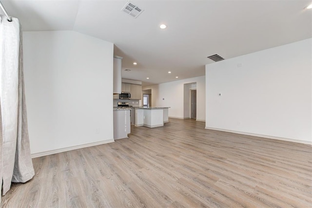 unfurnished living room featuring vaulted ceiling and light wood-type flooring