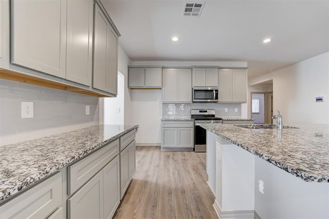 kitchen featuring gray cabinets, appliances with stainless steel finishes, sink, and light stone counters