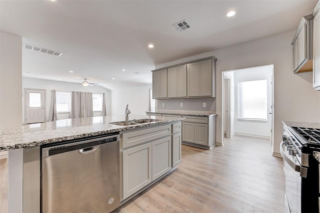 kitchen featuring stainless steel appliances, sink, gray cabinets, and a center island with sink