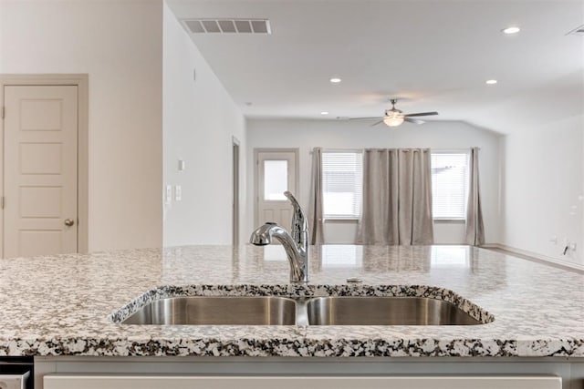 kitchen with sink, light stone countertops, and ceiling fan