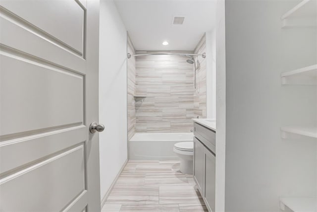 full bathroom featuring vanity, tiled shower / bath, and toilet