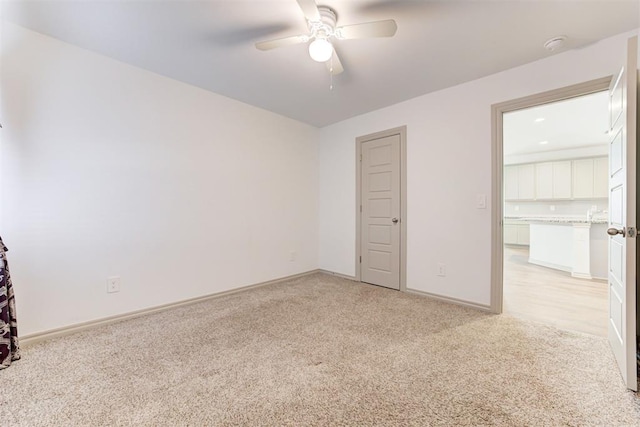 spare room featuring light colored carpet and ceiling fan