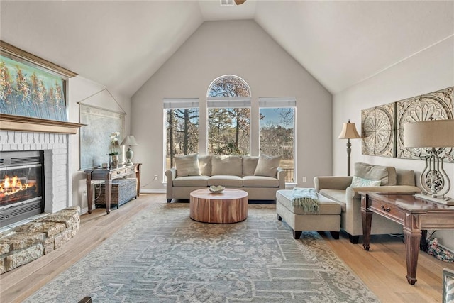 living room featuring vaulted ceiling, hardwood / wood-style floors, and a fireplace