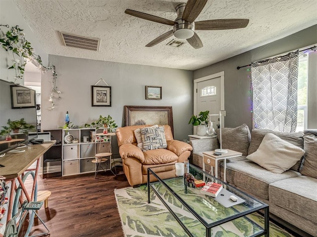 living room featuring dark hardwood / wood-style flooring, ceiling fan, and a textured ceiling