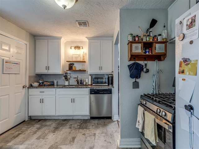 kitchen with white cabinetry, appliances with stainless steel finishes, sink, and decorative backsplash