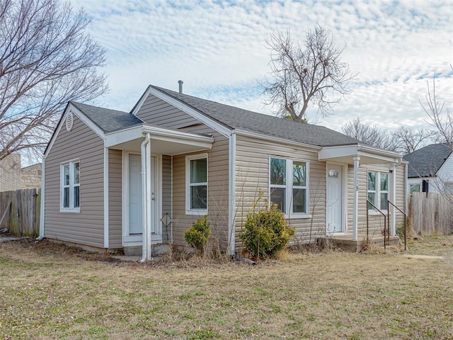 bungalow-style home with fence, a front lawn, and roof with shingles