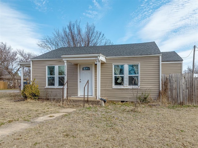 bungalow featuring a shingled roof and fence