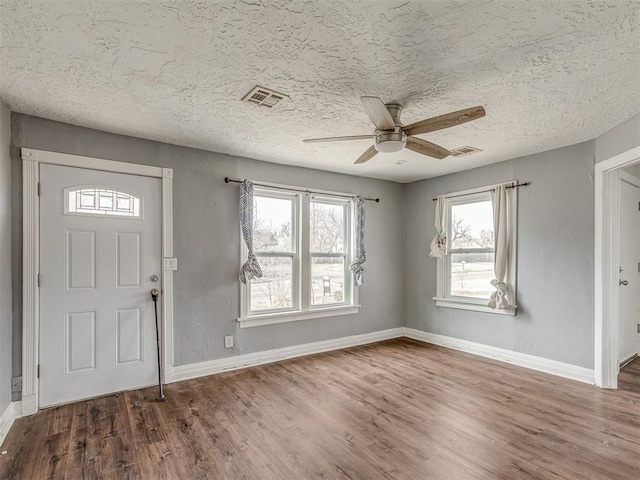 entrance foyer with visible vents, a textured ceiling, baseboards, and wood finished floors