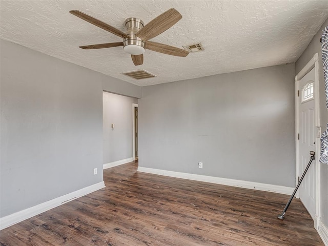 empty room with a ceiling fan, wood finished floors, visible vents, and baseboards