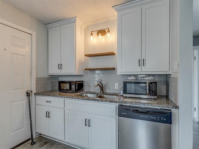 kitchen featuring open shelves, dark stone countertops, stainless steel appliances, and a sink