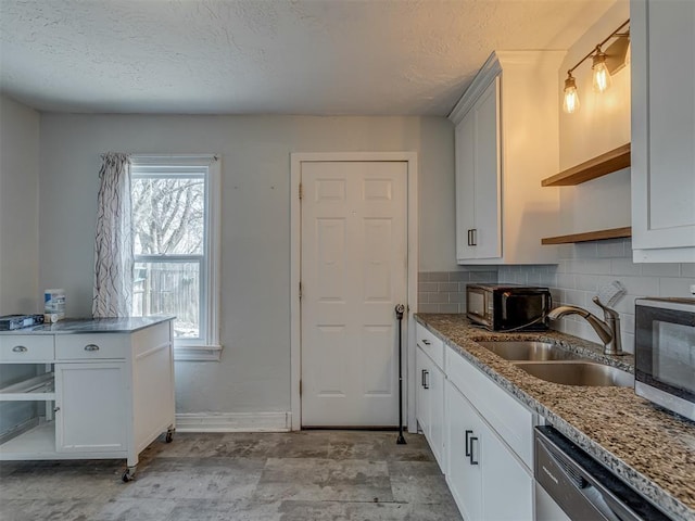 kitchen featuring light stone counters, open shelves, stainless steel appliances, tasteful backsplash, and a sink