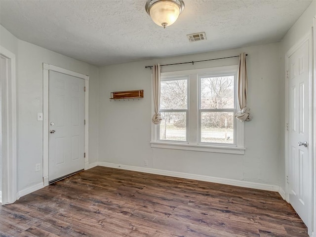 interior space with dark wood-style floors, visible vents, a textured ceiling, and baseboards