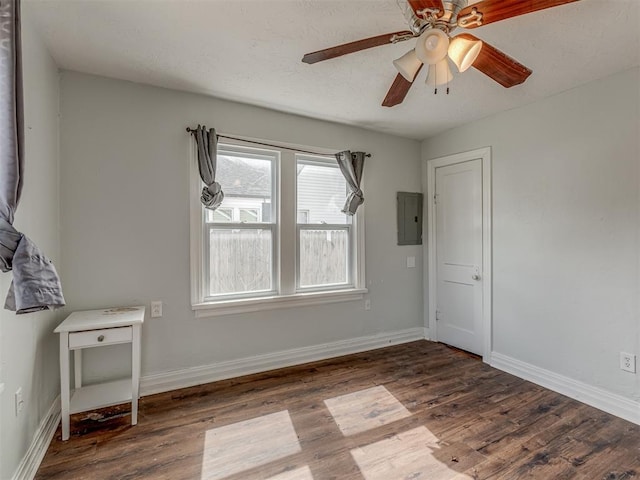 empty room with electric panel, baseboards, and wood finished floors