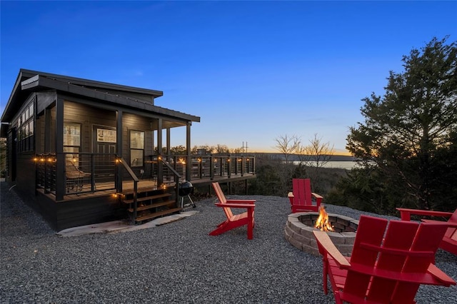 playground at dusk featuring a wooden deck and an outdoor fire pit