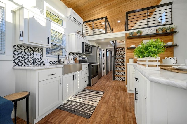 kitchen featuring white cabinetry, appliances with stainless steel finishes, wooden ceiling, and a wall unit AC