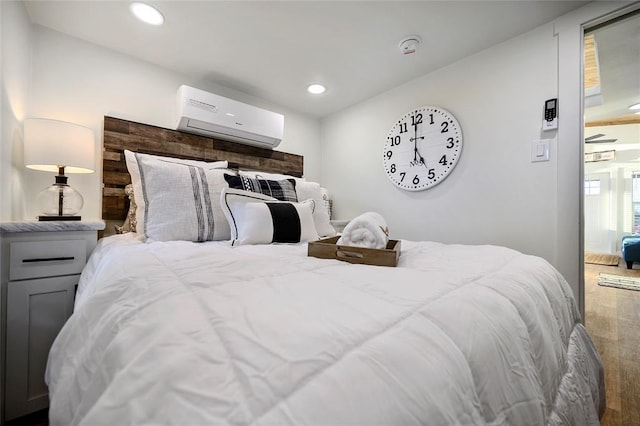 bedroom featuring hardwood / wood-style flooring and a wall mounted AC