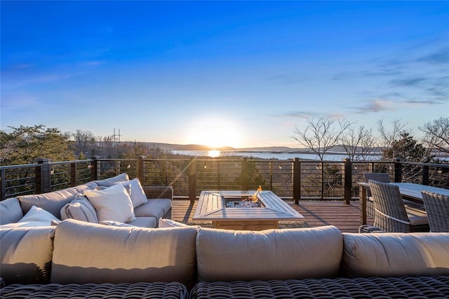 patio terrace at dusk featuring a wooden deck and an outdoor living space with a fire pit