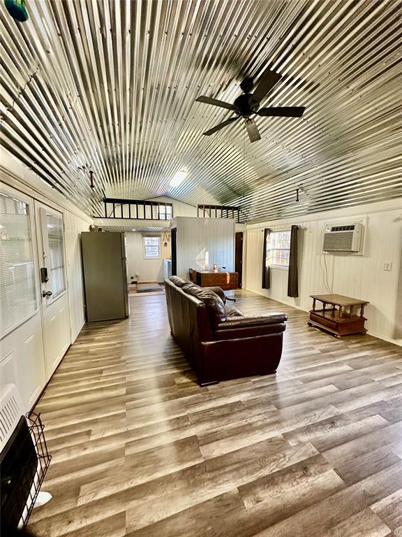 living room featuring a healthy amount of sunlight, a wall mounted air conditioner, ceiling fan, and light hardwood / wood-style flooring