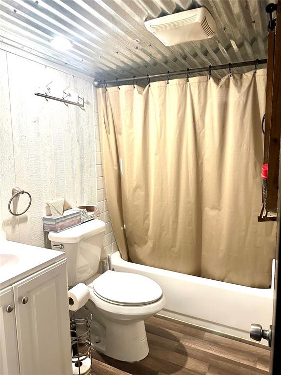 full bathroom with toilet, wood ceiling, wood-type flooring, vanity, and shower / bath combo