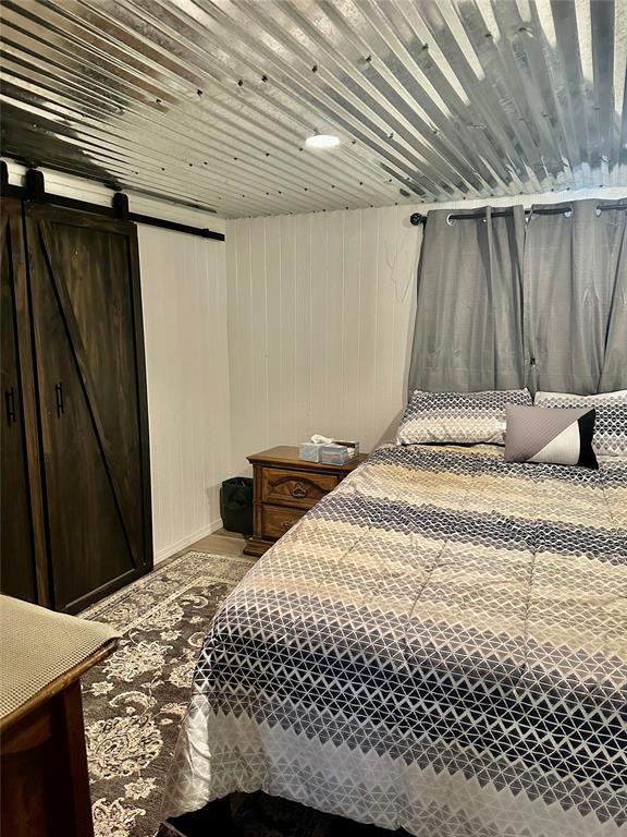 bedroom featuring wooden walls and a barn door