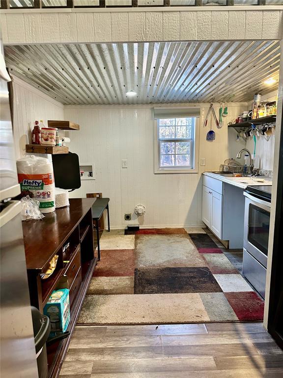 kitchen featuring sink, wood-type flooring, wood walls, and stainless steel electric range oven