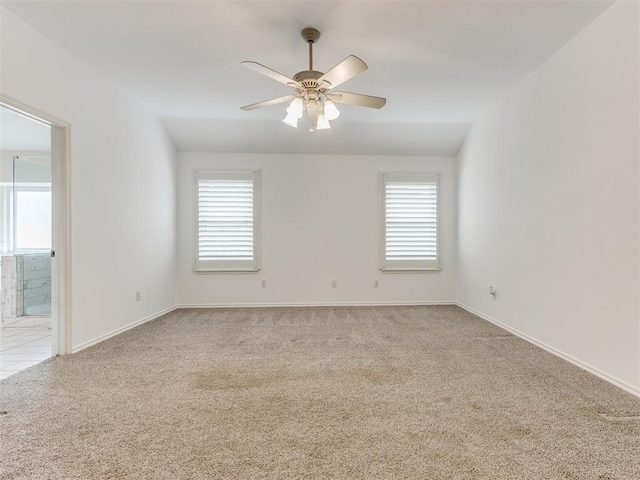 carpeted spare room featuring a wealth of natural light and ceiling fan