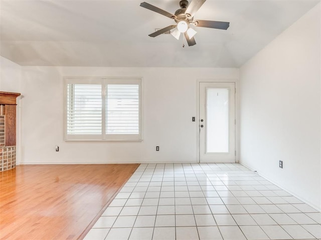 unfurnished living room with ceiling fan, vaulted ceiling, and light tile patterned floors