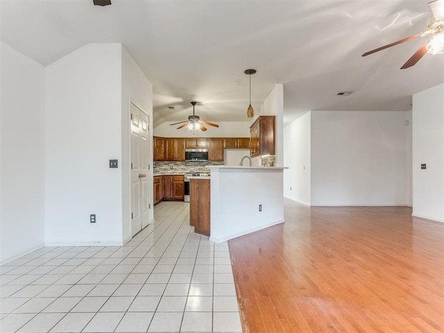 kitchen with pendant lighting, tasteful backsplash, light tile patterned floors, ceiling fan, and stainless steel appliances