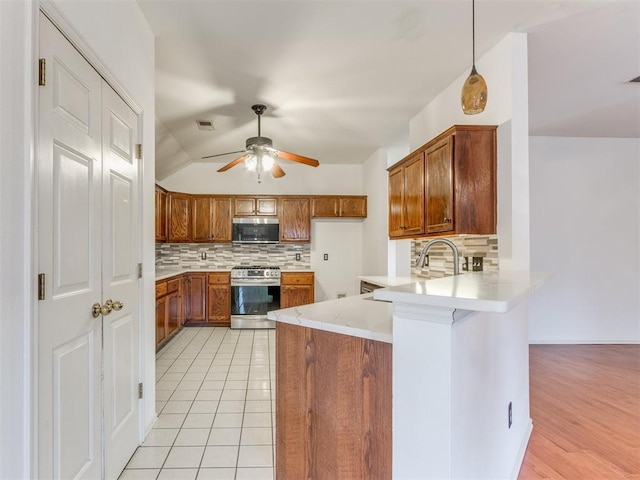 kitchen with a breakfast bar area, appliances with stainless steel finishes, hanging light fixtures, backsplash, and kitchen peninsula