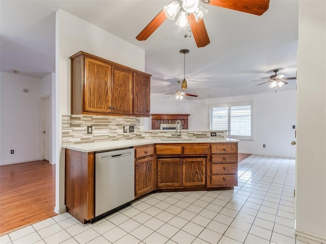 kitchen featuring light tile patterned flooring, sink, backsplash, stainless steel dishwasher, and kitchen peninsula