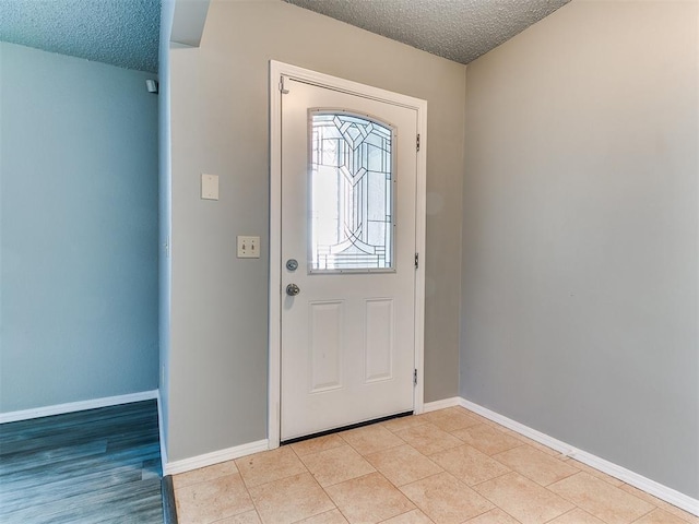 foyer entrance featuring a textured ceiling and light tile patterned flooring