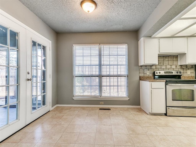 kitchen with light tile patterned floors, white cabinetry, backsplash, stainless steel electric stove, and french doors