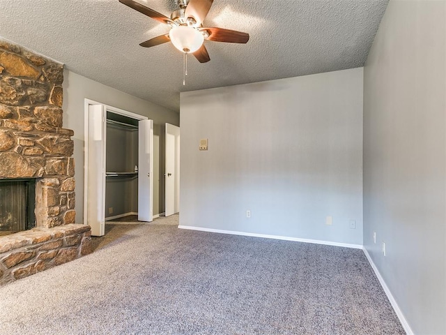 unfurnished bedroom featuring ceiling fan, carpet floors, a textured ceiling, a stone fireplace, and a closet